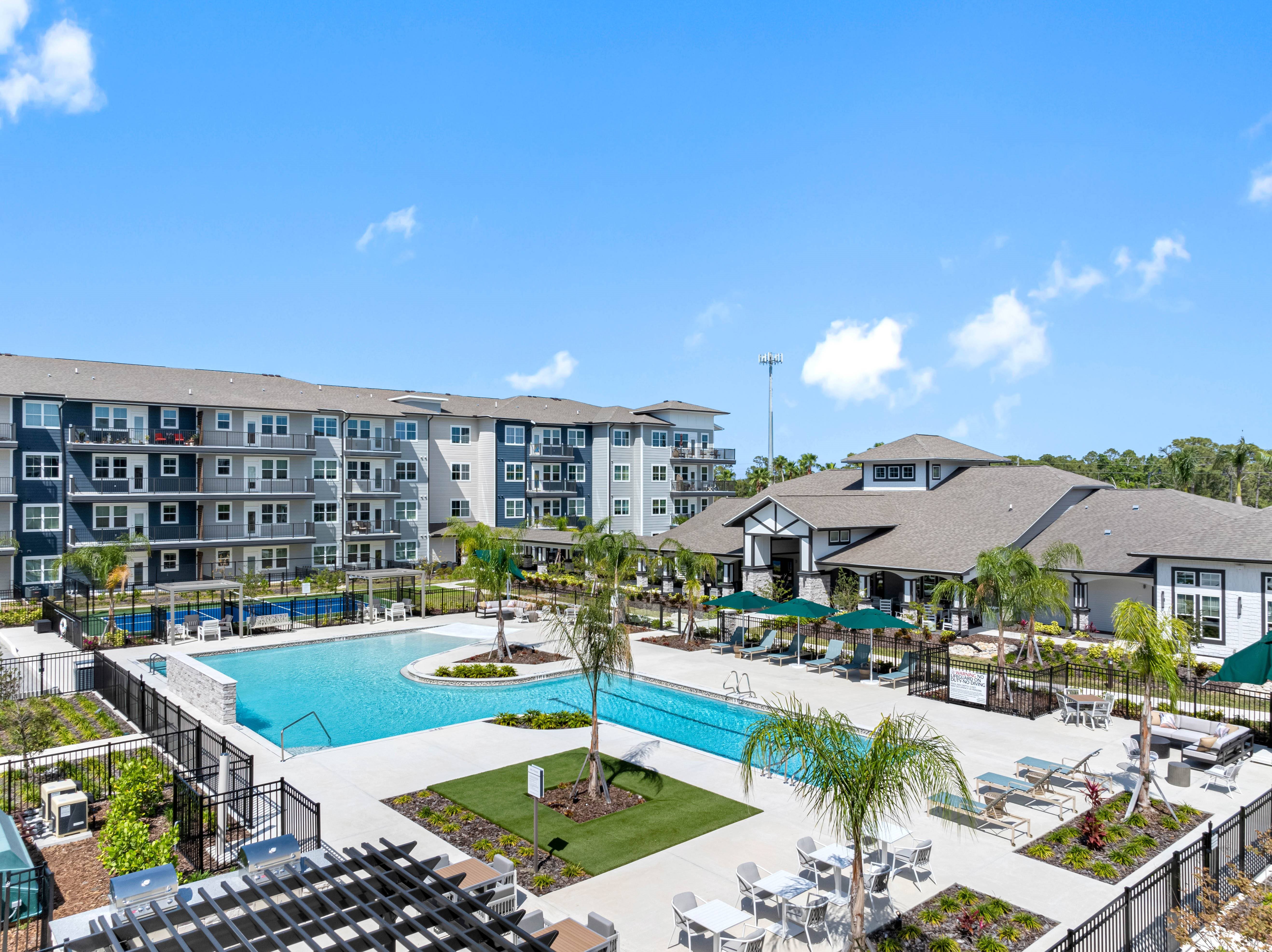A large swimming pool surrounded by a fence and chairs.